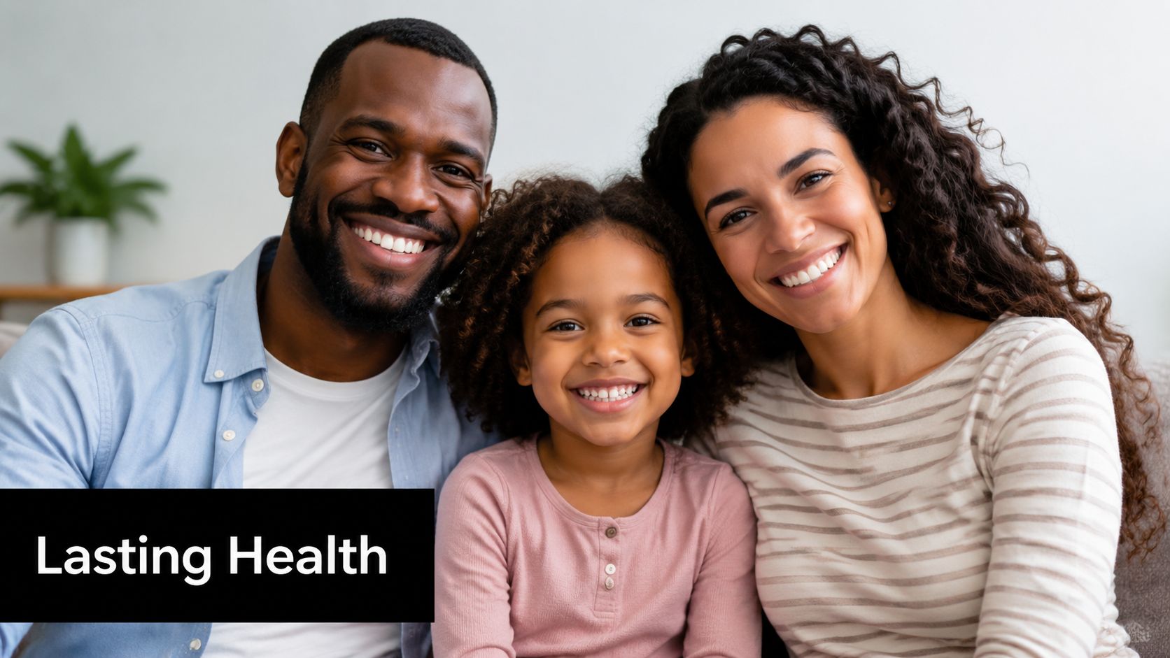 A happy diverse family consisting of a father, mother, and young daughter smiling together at home.